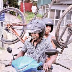 Thalangama-Individual wheels: An adult on a scooter transports a child with a bike