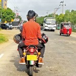 Puttalam Safety second: A pillion rider without a helmet, carries not one, but two helmets in hand Pic by Hiran Priyankara Jayasinghe