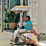 Bambalapitiya Childhood lost: A child hunkers down next  to an adult begging.