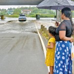 Kaduwela: Stranded duo: A woman and child wait near a flooded road.