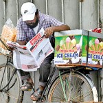 Maradana-  News bites: An ice cream vendor with few sales dut to the weather, catches up on happenings. Pix by Akila Jayawardena