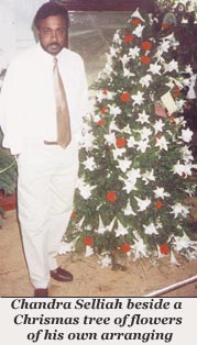 Chandra Selliah beside a Christmas tree of flowers of his own arranging