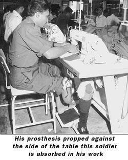 His prosthesis propped against the side of the table this soldier is absorbed in his work