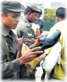 Troops checking a shoe when a group of people were stopped at a Colombo checkpoint.