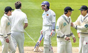 Sri Lanka's Kumar Sangakkara (C) looks back at his batting partner as New Zealand players Jamie How (L), Shane Bond, Stephen Fleming and Daniel Vettori (R) prepare to leave the field at the end of the Sri Lankan innings on the third day of the first test cricket match against New Zealand in Christchurch December 9, 2006.  REUTERS/Simon Baker   (NEW ZEALAND)