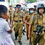 Flower Road What now: A young student looks on as Police file past. Pix by Eshan Fernando