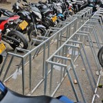 Vacant bicycle stand surrounded by motor bicycles.