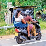 Kahathuduwa Hitching a ride: A pillion rider, without a helmet, finds a way around a constricting  garment.						Pic by Indika Handuwala