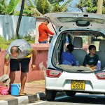 Wellawatte Quick dip: An adult washes the sand off kids' footwear after a beach trip.