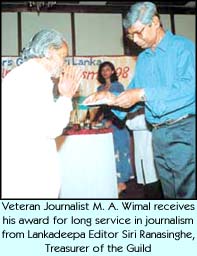 Veteran journalist M.A. Wimal receives his award for long service in journalism from Lankadeepa Editor Siri Ranasinghe, Treasurer of the Guild